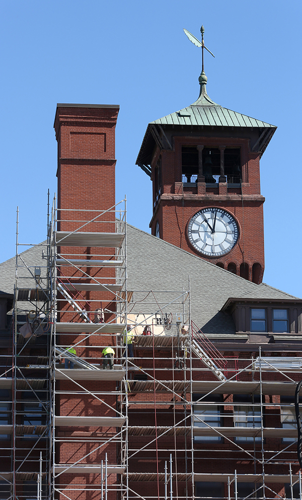 Workers on scaffolding repair the south side of Bowman Hall.