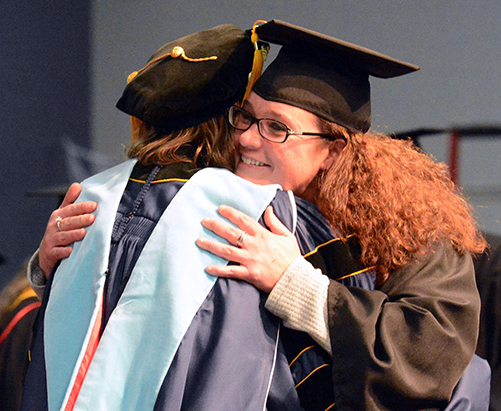 Dione Schumann hugs her program adviser while crossing the commencement stage Dec. 14.