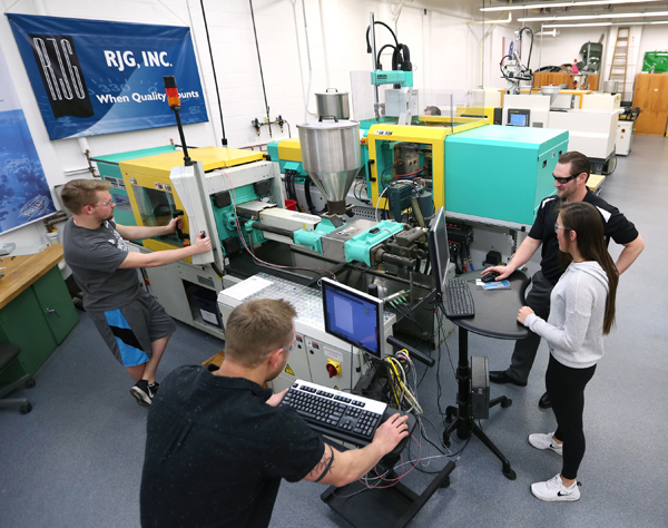 Students work with injecting molding machines in UW-Stout’s plastics engineering lab.