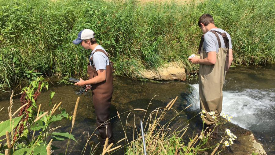 Kal Breeden, left, and Dylan Kostuch wade through a stream in Dunn County as part of the water monitoring program.