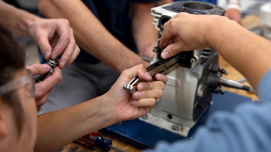 Mechanical engineering students disassembling a small engine