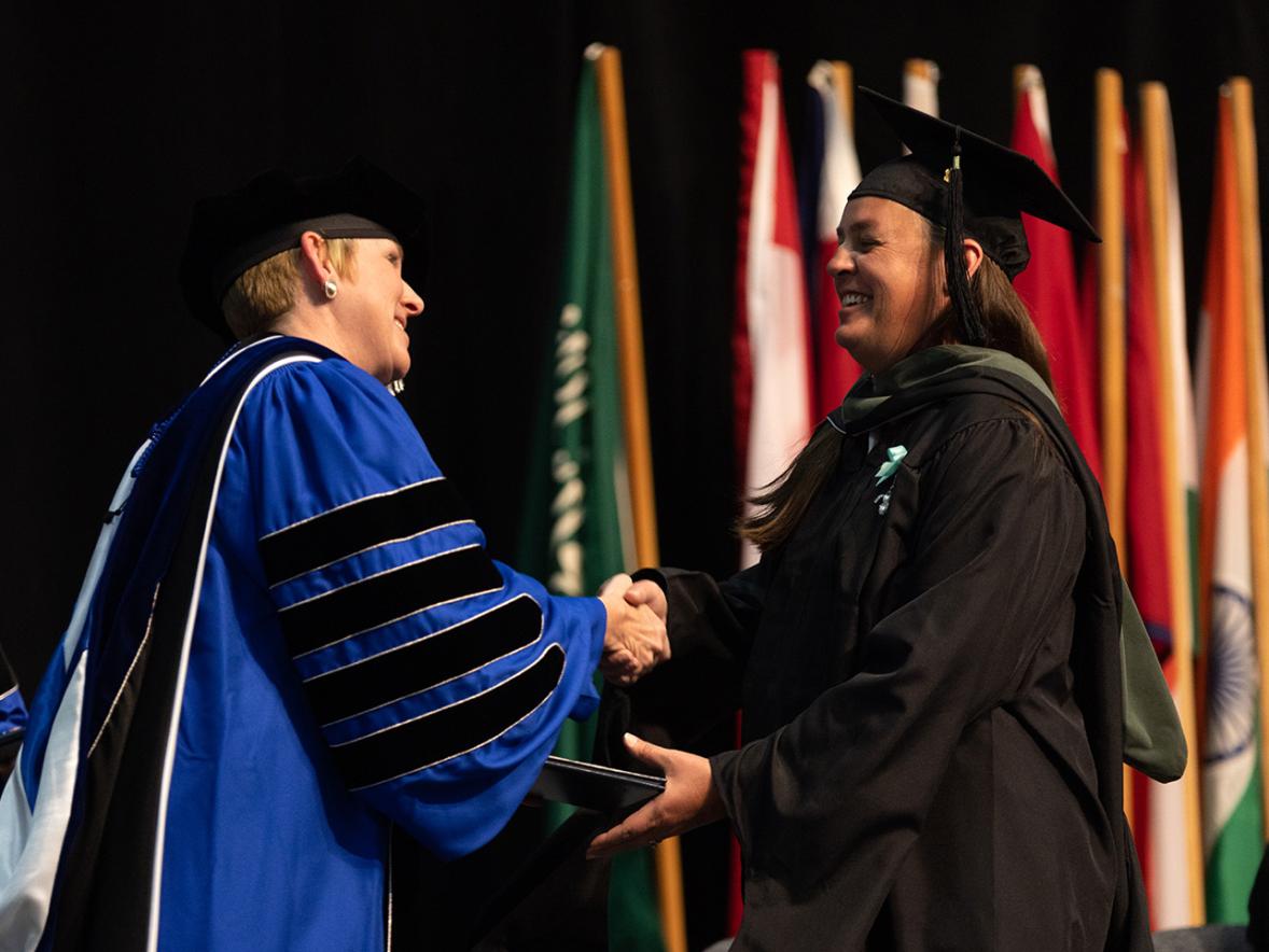 Jamie Stillion receiving her master's diploma from Chancellor Katherine Frank.