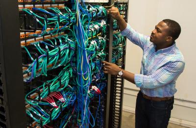 Emmanuel Mbanali in the telecom/network room at the UW-Stout Admin Building.